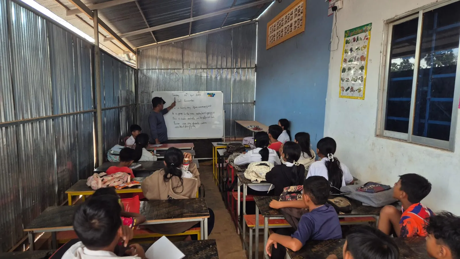 The CKP Foundation classroom — a teacher at the whiteboard with students at wooden desks